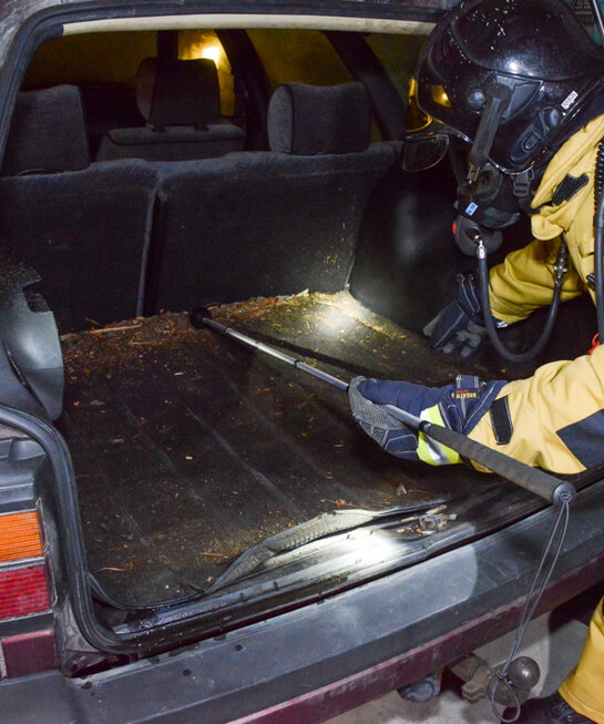 A fire service member searches an estate car's cargo compartment.