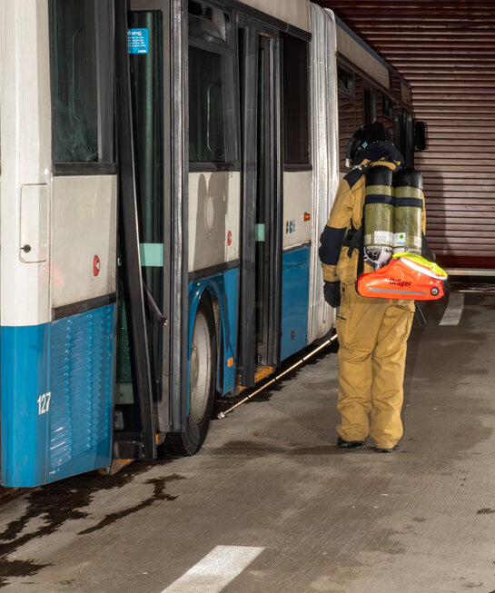 Feuerwehrmann tastet die Fläche entlang Bus ab