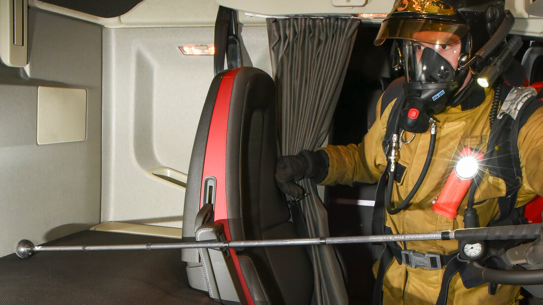 A firefighter searches the inside of a lorry driver's cab.