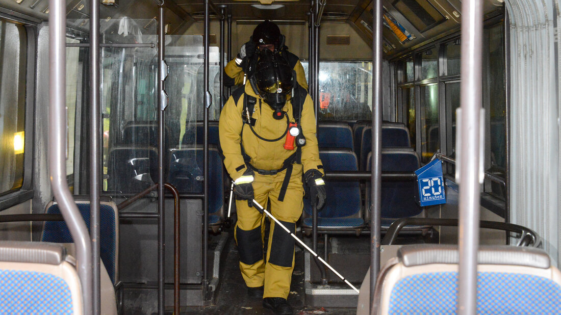 A firefighter searches the passenger area of a bus.