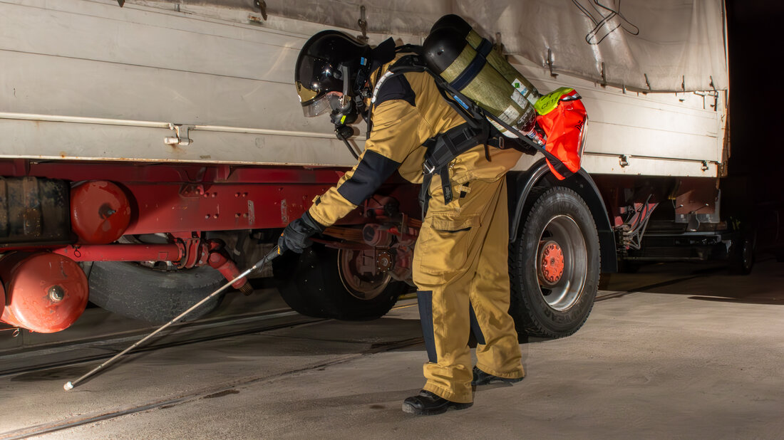 Feuerwehrangehöriger sucht Bereich unter einem LKW-Anhänger ab