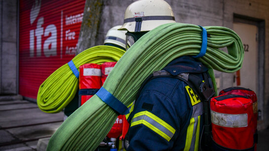 Feuerwehrmänner tragen Schlauchpakete