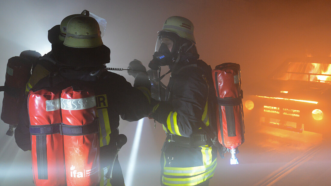 Practising communication in action Two firefighters communicate with each other using non-verbal communication during an operational drill