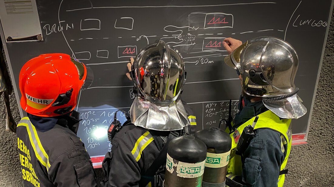 Feuerwehrangehörige erörtern das Vorgehen bei einem Löschangriff im Tunnel