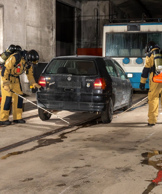 Feuerwehrangehörige suchen Bereiche entlang PKW ab.