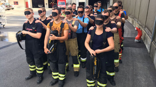 Feuerwehrangehörige mit Augenbinden bei einer Teambildungsübung